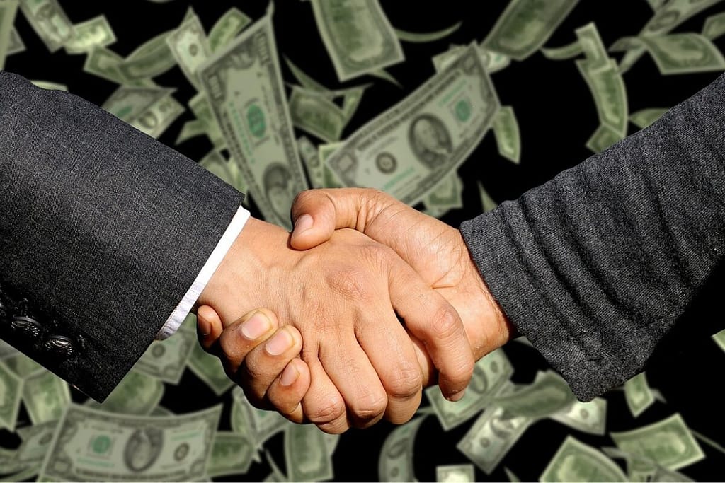 Hands shaking in front of a pile of money